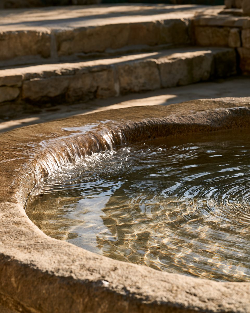 Clear water flowing gently into a hewn stone basin